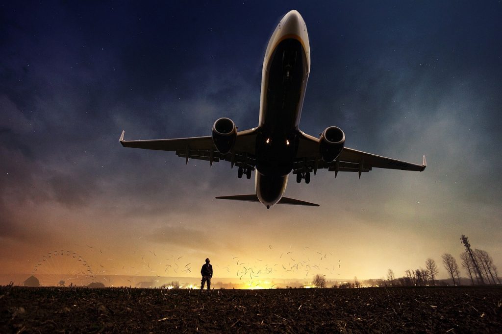 Man on the ground looking up at large jet flying overhead