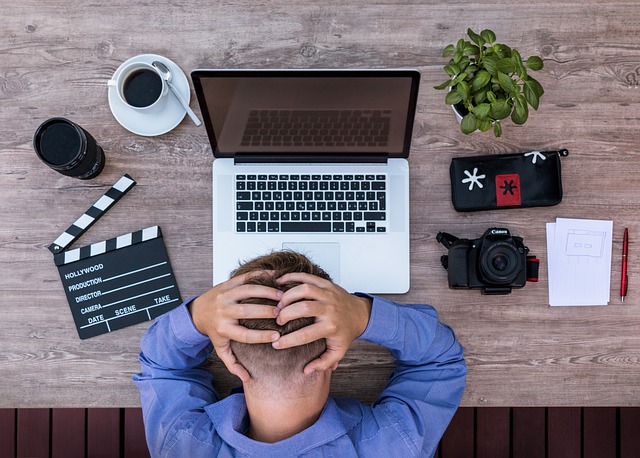 man at desk holding his head in frustration